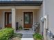 Inviting front entryway featuring a decorative glass door, covered porch, and lush landscaping at 11287 Cay Spruce Way, San Antonio, FL 33576