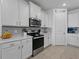 Well-lit kitchen features white cabinets, stainless steel appliances, and a decorative 