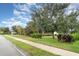 Well-manicured front yard of the property featuring a green lawn, mature trees, and a sidewalk at 11849 Forest Park Cir, Bradenton, FL 34211