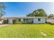 Charming single-story home features a well-manicured lawn, tidy landscaping, and a welcoming, light-blue front door at 1220 Magnolia Dr, Clearwater, FL 33756