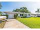 Inviting single-story home with lush lawn, attached garage, and a boat parked in the driveway at 1220 Magnolia Dr, Clearwater, FL 33756