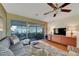 Cozy living room featuring a leafy rug, a large TV, and sliding glass doors to a sunroom at 1220 Magnolia Dr, Clearwater, FL 33756