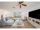 Comfortable living room features a plush gray sectional, wood-look floors, and a large window at 13013 Sawmill Way, Hudson, FL 34667