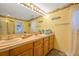 Bright bathroom with double sinks, wooden cabinets, and a large mirror at 18324 Jorene Rd, Odessa, FL 33556