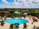 Aerial view of the outdoor pool with green umbrellas, lounge chairs, and manicured landscaping at 1906 Canterbury Ln # 20, Sun City Center, FL 33573