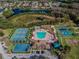 Aerial view of community amenities, including a pool, tennis courts, and recreational areas, nestled near a scenic pond at 19409 Weymouth Dr, Land O Lakes, FL 34638