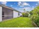Spacious backyard featuring green grass, a decorative birdhouse, and a screened-in porch of this well-maintained home at 19409 Weymouth Dr, Land O Lakes, FL 34638