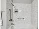 Bright bathroom with white marble tiled walls, brushed-nickel fixtures, and a shower-head niche for storage and decoration at 19409 Weymouth Dr, Land O Lakes, FL 34638