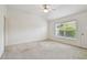 A bedroom with neutral carpeting, vaulted ceiling, ceiling fan, a window, and a door at 19409 Weymouth Dr, Land O Lakes, FL 34638