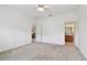 Spacious bedroom featuring neutral carpet, ceiling fan, and two entry doors at 19409 Weymouth Dr, Land O Lakes, FL 34638