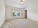 A bedroom with neutral carpeting, vaulted ceiling, ceiling fan, a window, and a door at 19409 Weymouth Dr, Land O Lakes, FL 34638