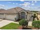 Single-story home featuring a two-car garage, landscaped front yard, and an arched window adding architectural detail at 19409 Weymouth Dr, Land O Lakes, FL 34638