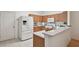 Bright kitchen features white appliances, wooden cabinets, and a breakfast bar overlooking the adjacent living area at 19409 Weymouth Dr, Land O Lakes, FL 34638