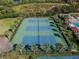 Aerial view of the tennis courts with beautiful landscaping and mature palm trees at 19409 Weymouth Dr, Land O Lakes, FL 34638