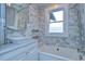 Bright bathroom featuring a white marble tiled wall, pedestal sink, and modern bathtub with updated fixtures at 205 W Emma St, Tampa, FL 33603