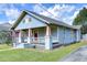 Single-story home with quaint porch and yard featuring detailed architectural elements under a sunny, partly cloudy sky at 205 W Emma St, Tampa, FL 33603