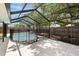 Outdoor pool area featuring a screened enclosure, concrete deck, mature tree, and fenced yard at 2066 62Nd Pl S 62Nd Pl, St Petersburg, FL 33712