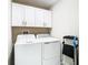 This laundry room features white cabinets above a GE washer and dryer at 2190 Great Sapphire Ln, Lutz, FL 33558