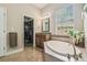 Bright bathroom with a soaking tub, large window, and entrance to a walk-in closet at 32015 Summerglade Dr, Wesley Chapel, FL 33545