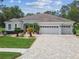 Beautiful single-story home with a three-car garage, paver driveway, and professionally landscaped front yard at 32015 Summerglade Dr, Wesley Chapel, FL 33545