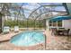 Relaxing screened-in pool area with brick patio, dining set, lounge chairs and calming views of pond and lush greenery at 32015 Summerglade Dr, Wesley Chapel, FL 33545