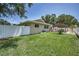 Expansive backyard with a white fence, lush green lawn, and a charming covered patio area at 3242 Brushwood Ct, Clearwater, FL 33761