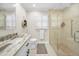Bright bathroom featuring marble countertop, walk-in shower with glass door, and white plantation shutters at 3242 Brushwood Ct, Clearwater, FL 33761