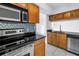 Kitchen featuring stainless steel appliances, granite counters, warm wood cabinets, and mosaic backsplash at 3300 Haviland Ct # 103, Palm Harbor, FL 34684