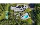 Aerial shot of a luxurious estate with a sparkling pool, tennis court, lush gardens, and modern solar panels at 3425 W Forest Lake Cir, Sarasota, FL 34232