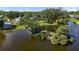 Aerial view of the property highlighting the lake, dock, mature trees, and expansive lawn at 3425 W Forest Lake Cir, Sarasota, FL 34232