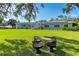 Inviting backyard seating area under a large tree with view of the home, lush lawn and fence at 3425 W Forest Lake Cir, Sarasota, FL 34232