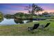 Relaxing backyard with two lounge chairs by the lake and dock, complemented by a stunning sunset backdrop at 3425 W Forest Lake Cir, Sarasota, FL 34232