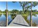 A tranquil gray wooden dock extends into a serene lake surrounded by lush greenery and a clear blue sky at 3425 W Forest Lake Cir, Sarasota, FL 34232