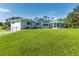 Expansive single Gathering home featuring large windows, light gray exterior and solar panels, all set on an expansive lawn at 3425 W Forest Lake Cir, Sarasota, FL 34232