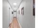 The hallway features a light gray paint, wood floors, bright recessed lighting, and neutral artwork at 3425 W Forest Lake Cir, Sarasota, FL 34232