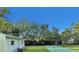 Private outdoor tennis court adjacent to a building, set against a backdrop of lush trees at 3425 W Forest Lake Cir, Sarasota, FL 34232