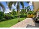 Lush backyard with mature palm trees, green lawn, and brick patio area at 3673 Fremantle Dr, Palm Harbor, FL 34684