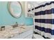 Updated bathroom featuring a marble vanity, chrome hardware, and blue-striped shower curtain at 3673 Fremantle Dr, Palm Harbor, FL 34684