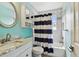 Bright bathroom with a marble-top vanity, round mirror, and blue striped shower curtain at 3673 Fremantle Dr, Palm Harbor, FL 34684