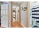 Hallway with wood floors leading to a bathroom with a blue striped shower curtain at 3673 Fremantle Dr, Palm Harbor, FL 34684
