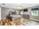 Spacious primary bedroom featuring wood floors, ceiling fan, TV, and many windows for natural light at 37331 Hickory Hill Ln, Dade City, FL 33525