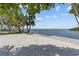 Bayfront backyard featuring a seating area and sandy shoreline leading to tranquil water views at 4749 Baywood Point S Dr, Gulfport, FL 33711