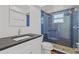 Modern bathroom featuring a blue-tiled shower with glass doors, granite countertop and new toilet at 4749 Baywood Point S Dr, Gulfport, FL 33711