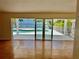 Bright living room featuring sliding glass doors opening to a waterfront pool and bay views at 4749 Baywood Point S Dr, Gulfport, FL 33711