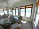 A sunny sunroom with large windows that have serene ocean views, with seating around glass top table at 4950 Gulf Blvd # 404, St Pete Beach, FL 33706