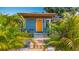 Quaint home featuring a striking orange door and lush tropical landscaping at 5005 Tangerine S Ave, Gulfport, FL 33707