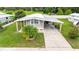 Aerial view of a cozy home with a carport, surrounded by lush greenery and a well-kept lawn at 5451 Antigua Dr, Zephyrhills, FL 33541