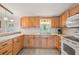 Well-lit kitchen with light wood cabinets, neutral countertops, white appliances and tile floor at 5451 Antigua Dr, Zephyrhills, FL 33541