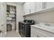 Efficient laundry room with modern washer, dryer, built-in cabinets, sink, and storage shelves at 6129 Marsh Trail Dr, Odessa, FL 33556