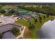 Aerial view of the community tennis courts, landscaping, and nearby pond at 624 La Jolla Ave, Sun City Center, FL 33573